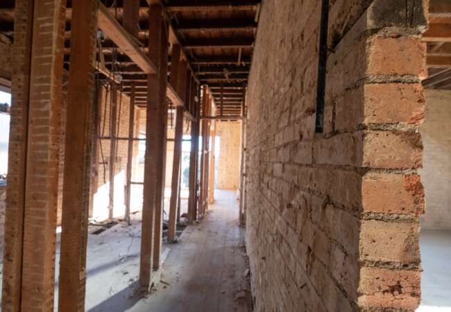 Interior in fit-out progression including exposed brickwork, unfinished floors