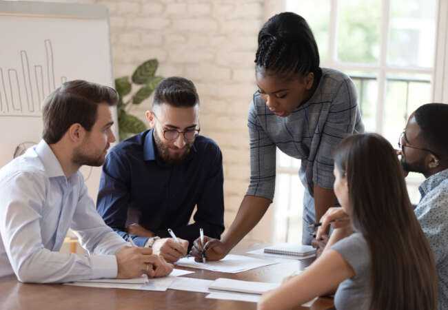 Managers in meeting stood and sat around table