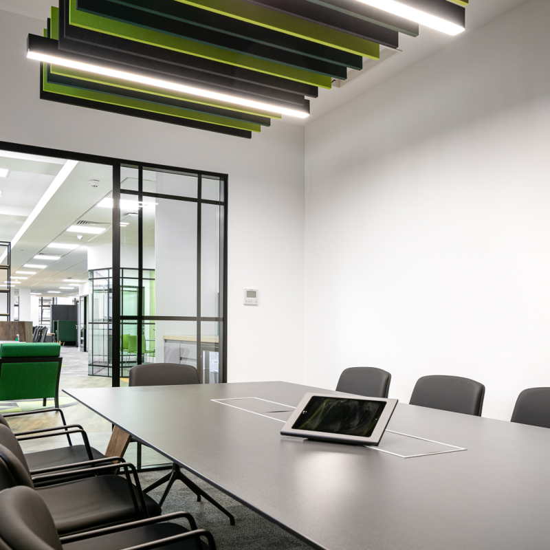 meeting room with AV and acoustic ceiling panels looking out towards open offices