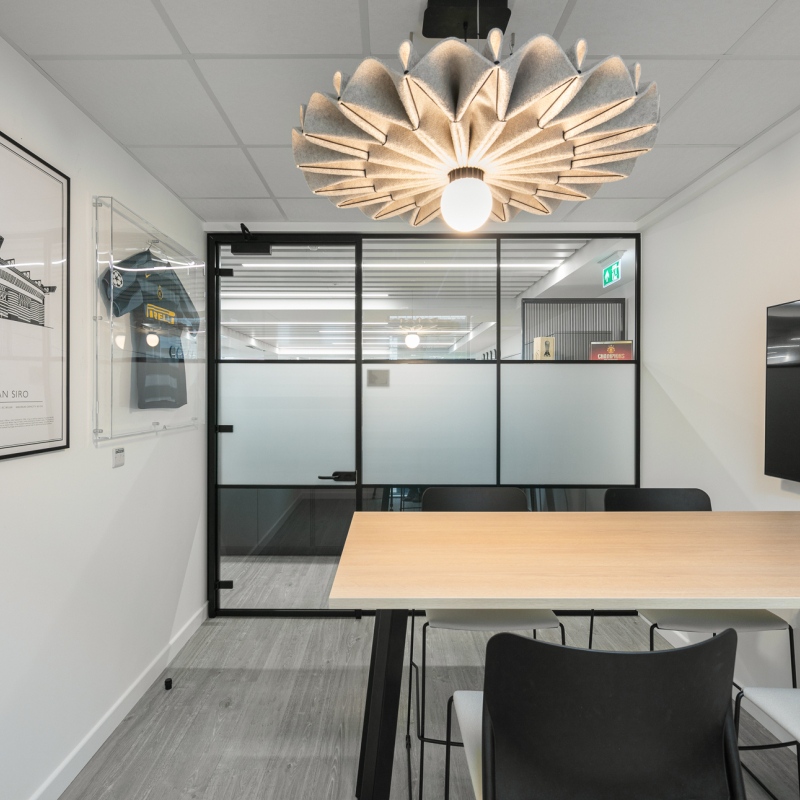 video conference room with wall art, high meeting table and 4 high stools