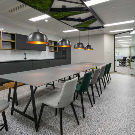 kitchen break out space with tables and chairs central location and pendent lighting